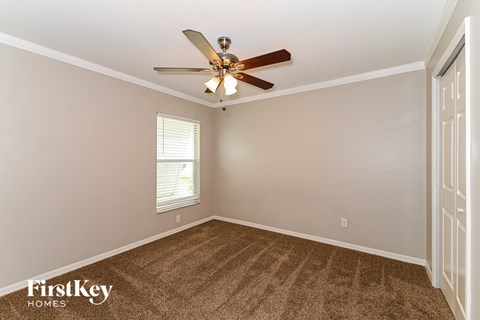 a living room with a ceiling fan and a carpet