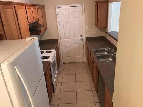A white refrigerator is in the kitchen with a white door.