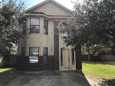 A house with a brown brick wall and a white door.