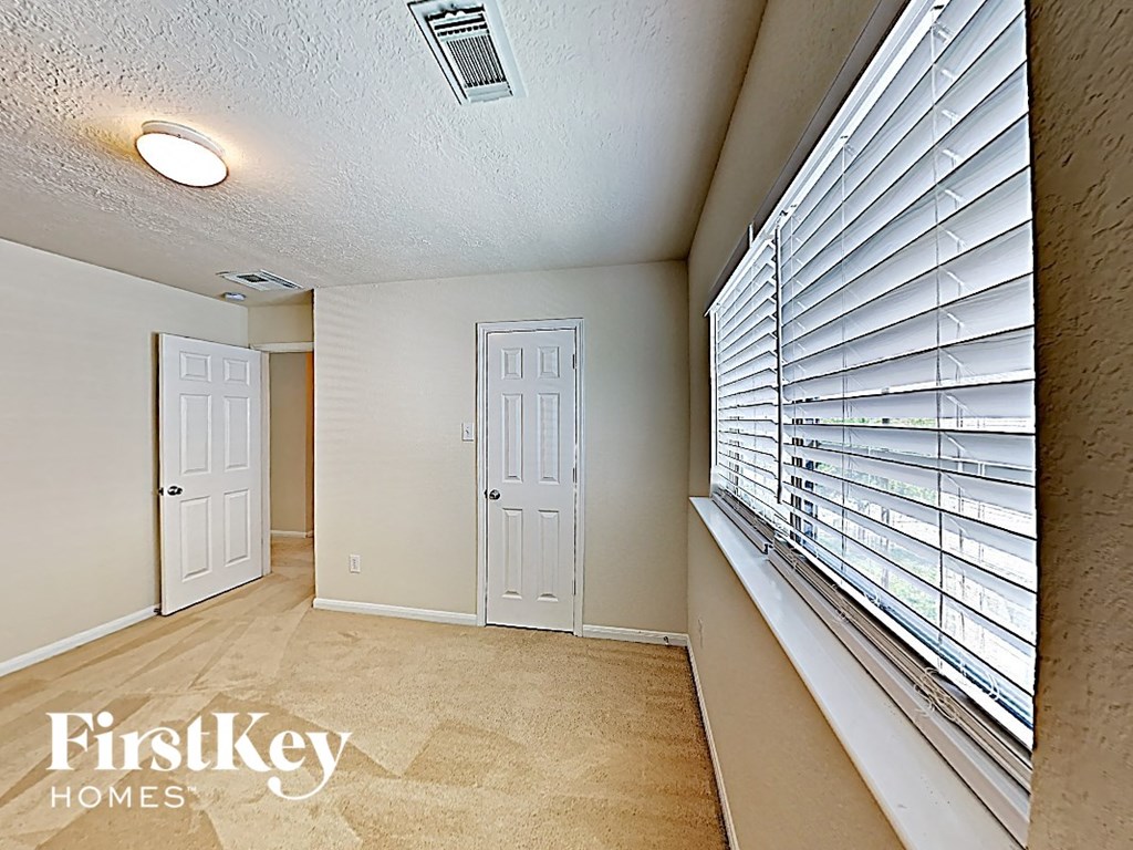 a hallway with a large window with white blinds and a white door