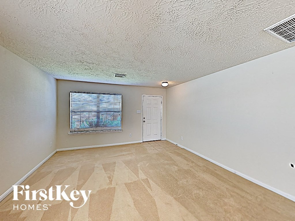 an empty living room with a window and a door