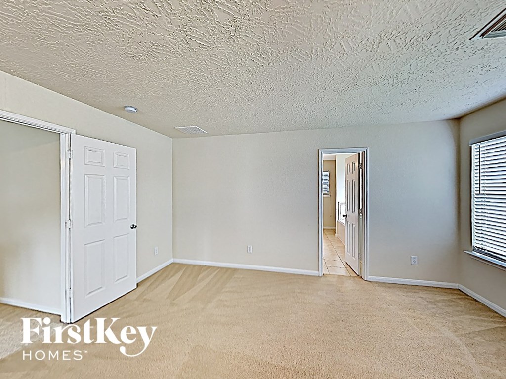 a bedroom with a door to the hallway and a carpeted floor