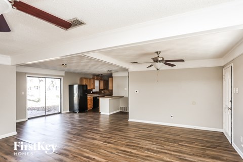 A spacious room with wooden floors and a ceiling fan.
