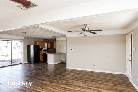 A spacious room with wooden floors and a ceiling fan.
