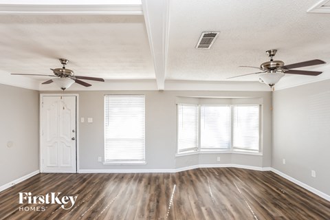 A room with wooden floors and two ceiling fans.