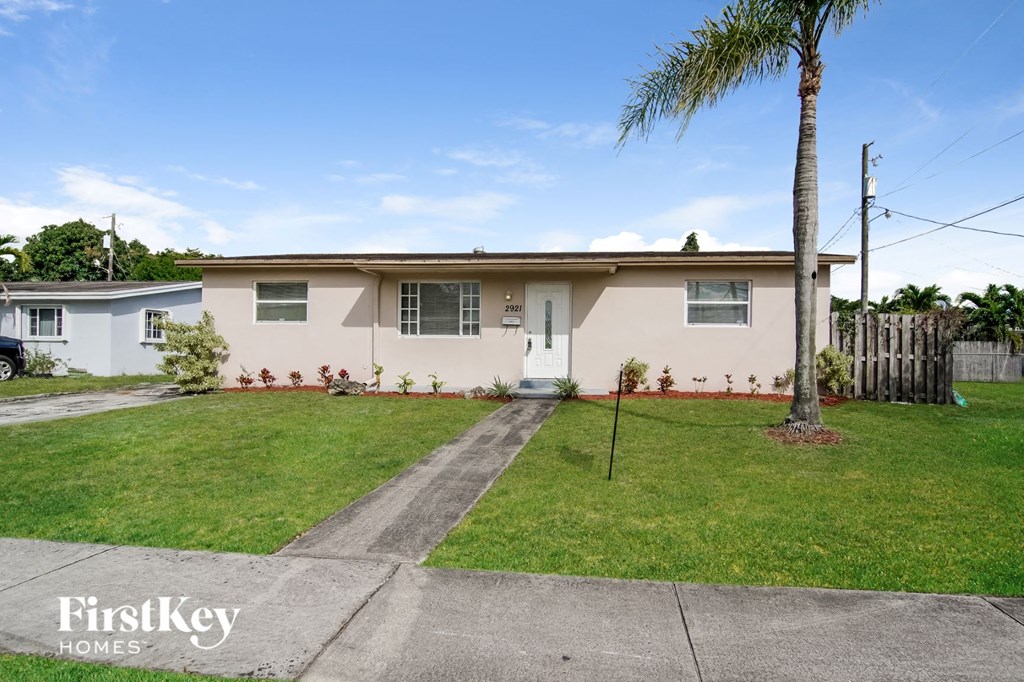 a home with a lawn and palm tree in front of it