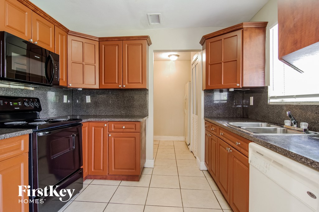 a kitchen with wooden cabinets and black appliances and white countertops