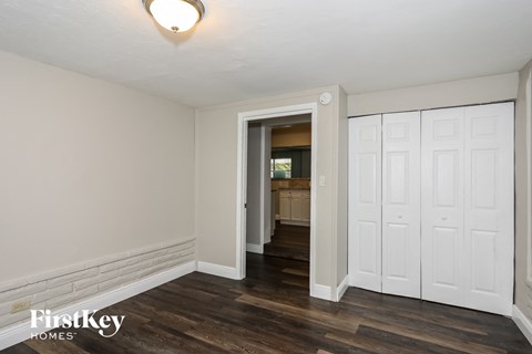 the living room of an apartment with white walls and wood floors