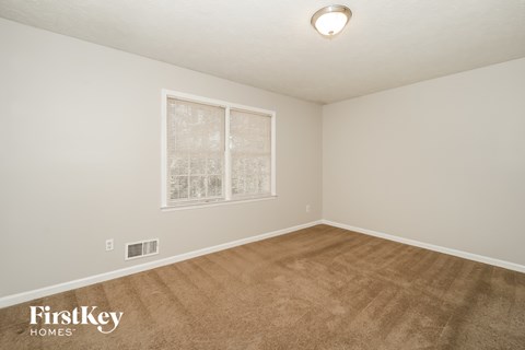 a spacious living room with carpet and a window