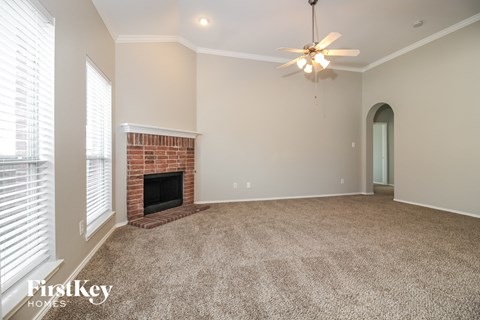 a living room with a brick fireplace and a ceiling fan