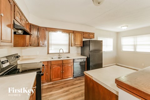 A kitchen with wooden cabinets and a black refrigerator.