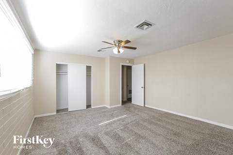 a spacious living room with carpet and a ceiling fan
