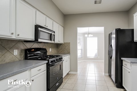 A kitchen with white cabinets and black appliances.