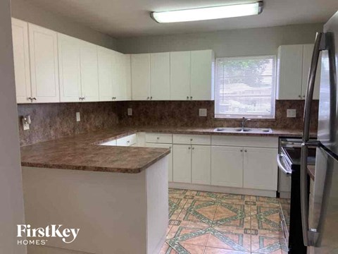 A kitchen with a tile floor and a refrigerator.