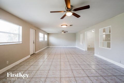 an empty living room with a ceiling fan and a tiled floor