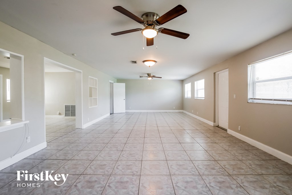 an empty living room with a ceiling fan and a tiled floor