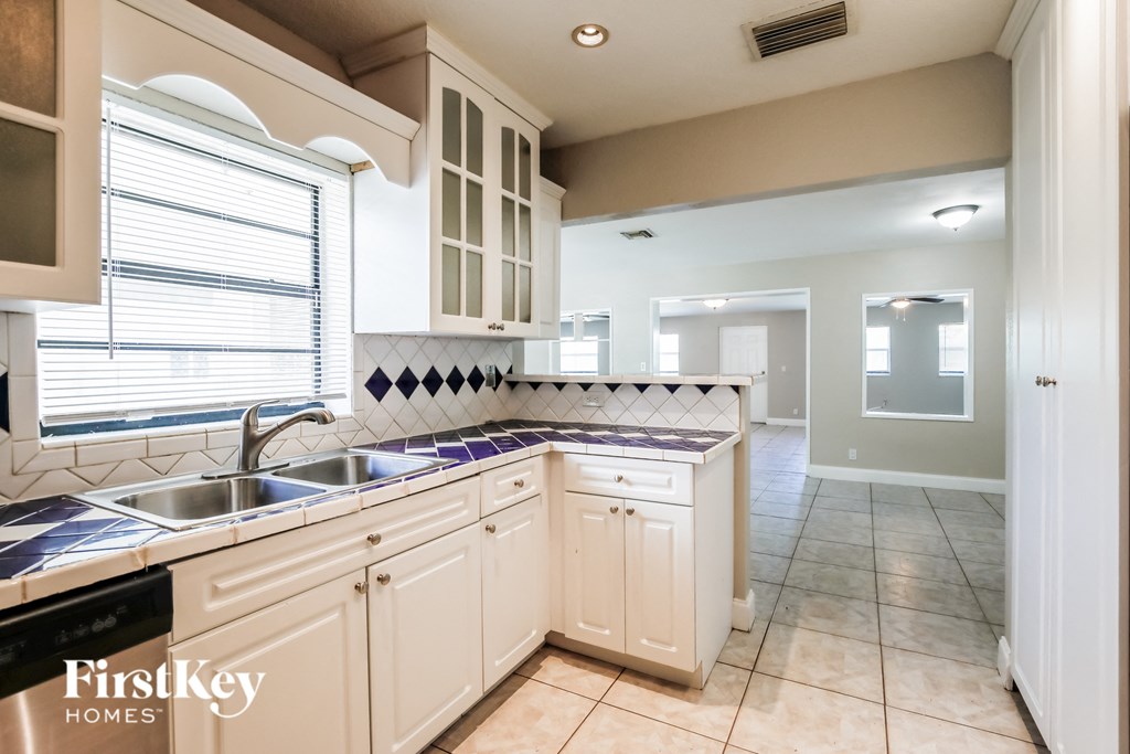 a kitchen with white cabinets and a sink and a window