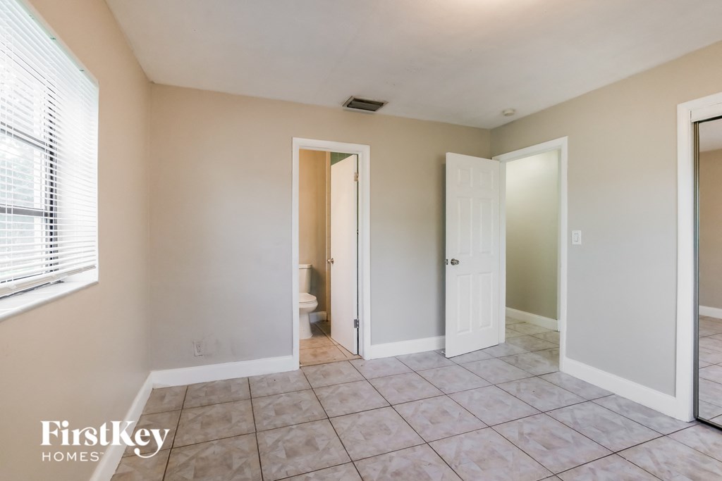 the living room of an empty home with a tiled floor and a white door