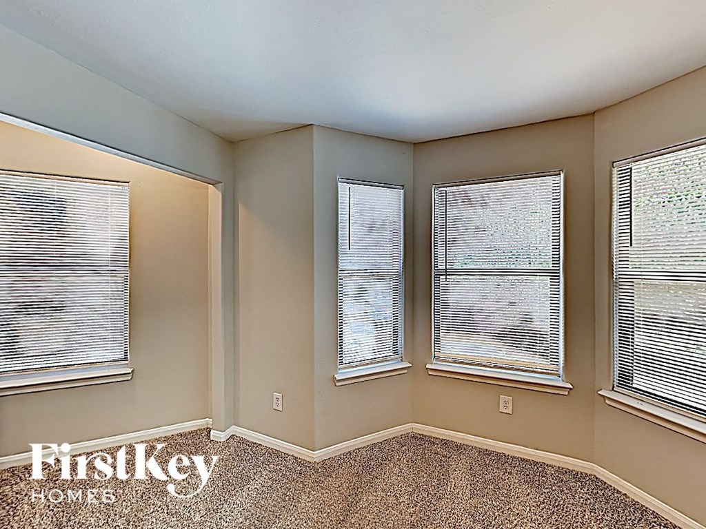 an empty bedroom with three windows with blinds and a window sill