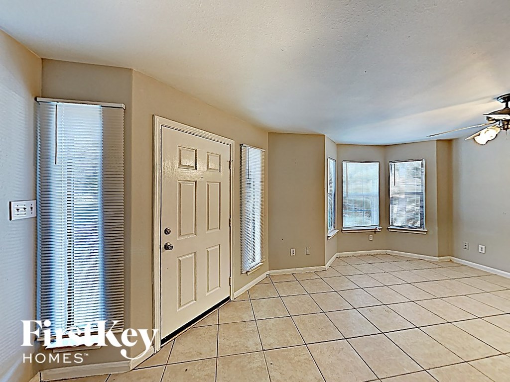 an empty living room with a white door and windows