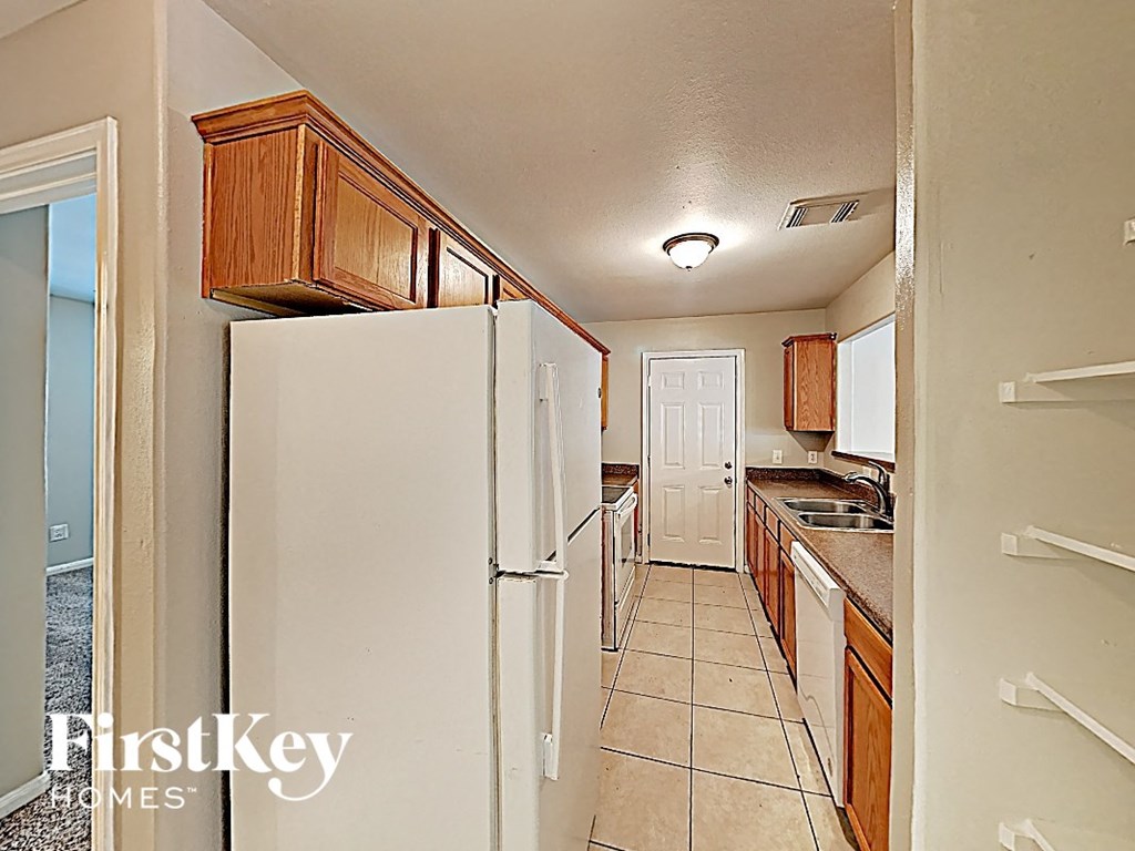 a small kitchen with a refrigerator and a door to the bathroom
