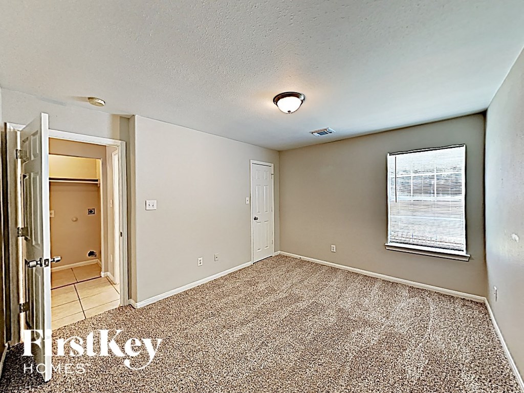 an empty bedroom with a door to the bathroom and a window