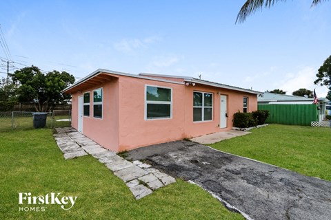 A pink house with a stone pathway leading to the front door.