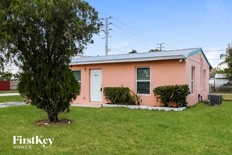 A pink house with a tree in front of it.