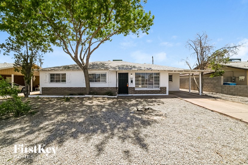 A house with a gravel driveway and a tree in front.