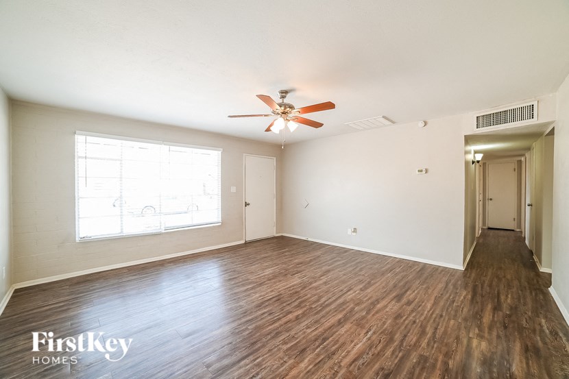 A spacious room with wooden floors and a ceiling fan.