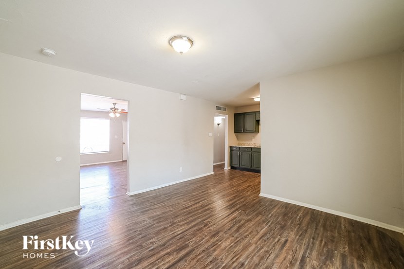 A spacious room with wooden flooring and a flat screen TV mounted on the wall.