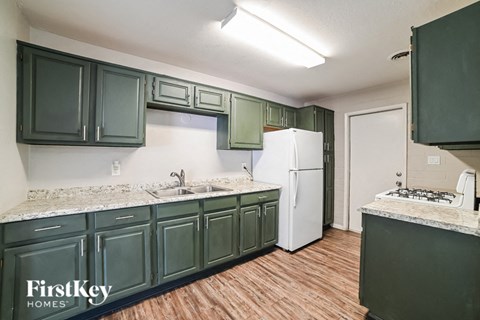 A kitchen with green cabinets and a white fridge.