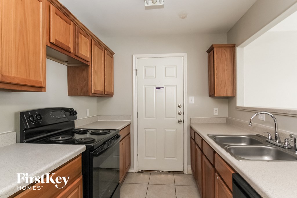 a kitchen with wood cabinets and black appliances and a white door