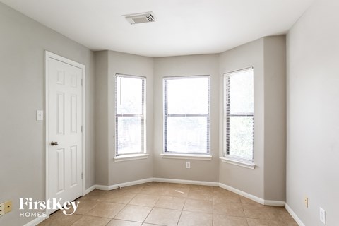 a living room with three windows and a white door