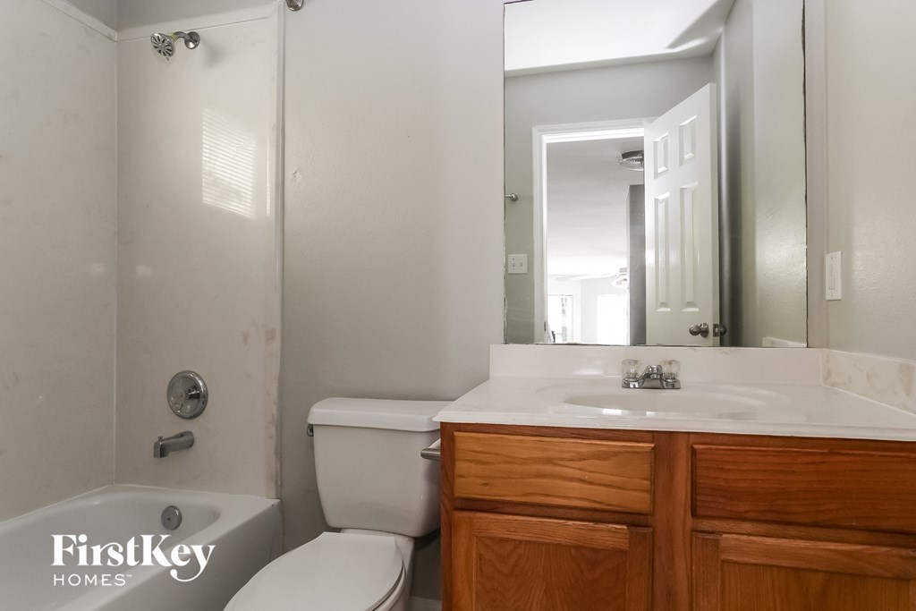 a bathroom with a toilet sink and mirror and a shower
