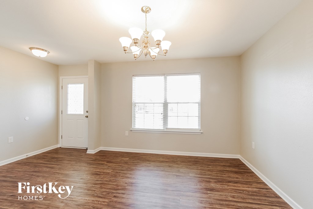 the spacious living room with wood flooring and a chandelier