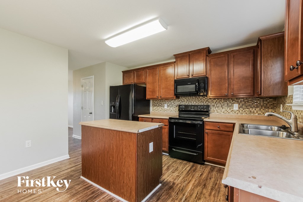 an empty kitchen with wooden cabinets and black appliances