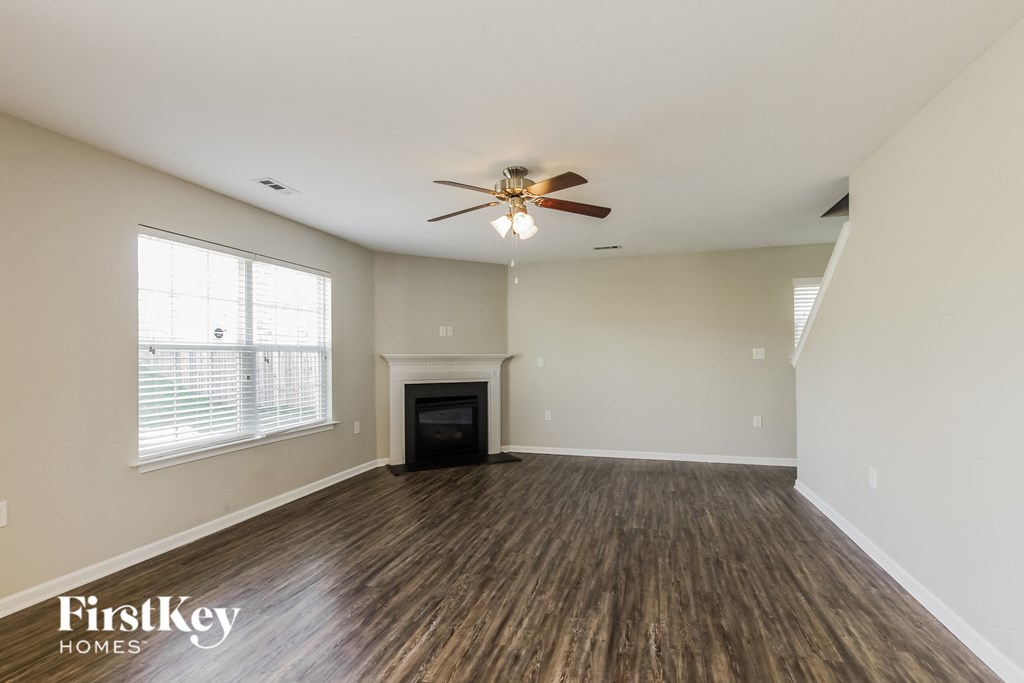 an empty living room with a ceiling fan and a fireplace