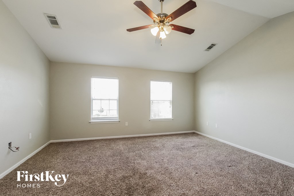 an empty room with a ceiling fan and two windows