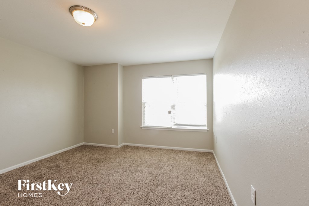 a spacious bedroom with carpet and a window