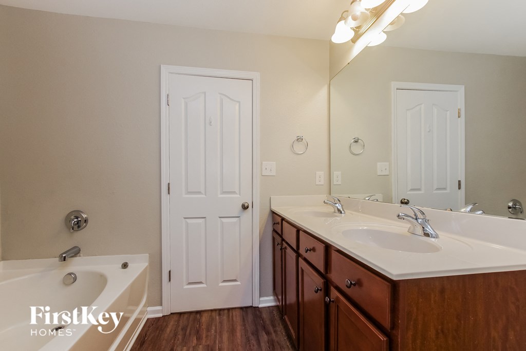 a bathroom with two sinks and a tub and a mirror