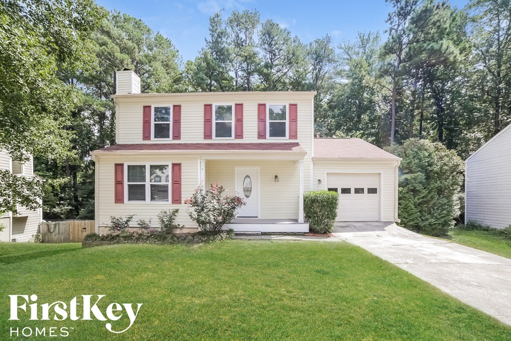 a white house with red shutters and a lawn