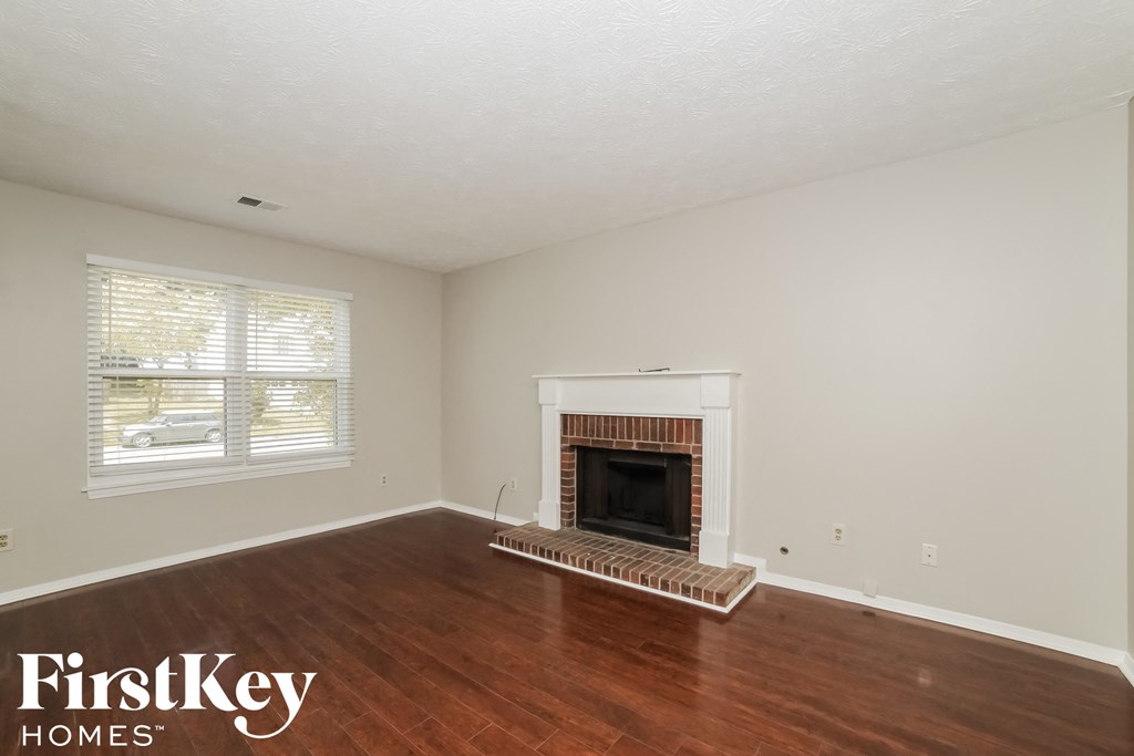 the living room of a house with a fireplace and wooden floors