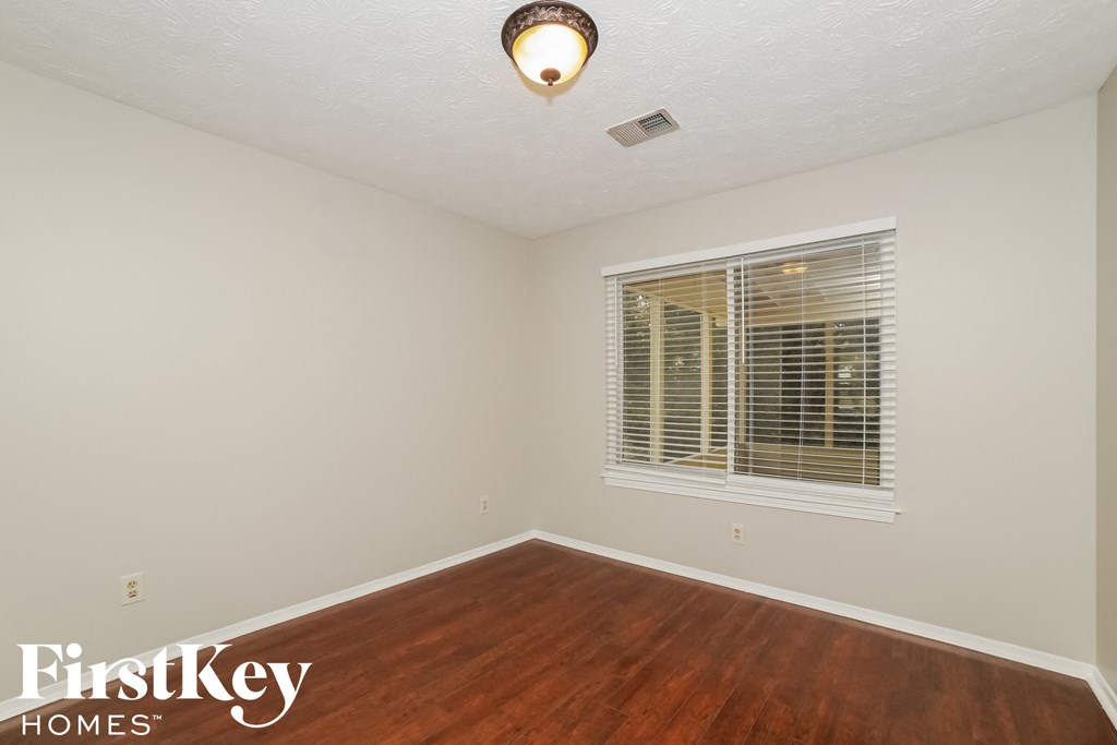 a bedroom with wood flooring and a large window