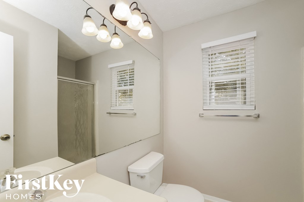 a bathroom with a mirror and a toilet and a shower
