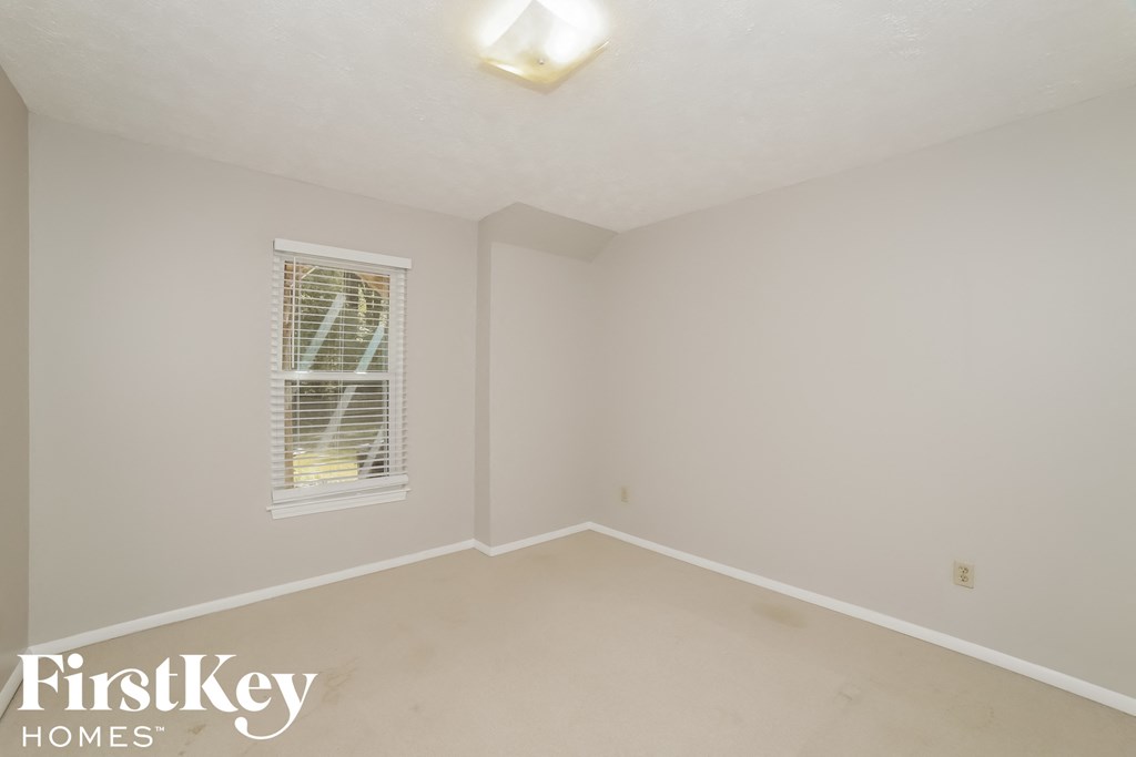 a bedroom with white walls and a window
