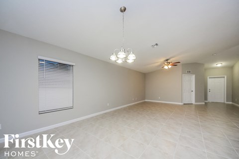 A spacious room with a fan and a chandelier.