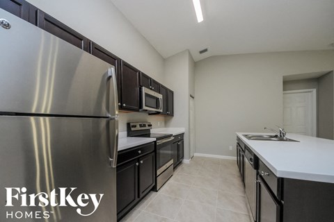 A kitchen with a stainless steel refrigerator and black cabinets.