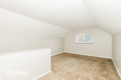 a bedroom with white walls and carpet and a window