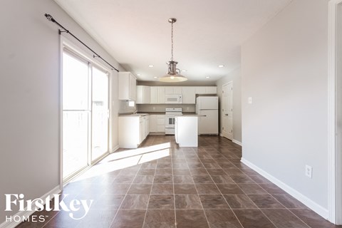 A well-lit kitchen with tile flooring and a hanging light fixture.